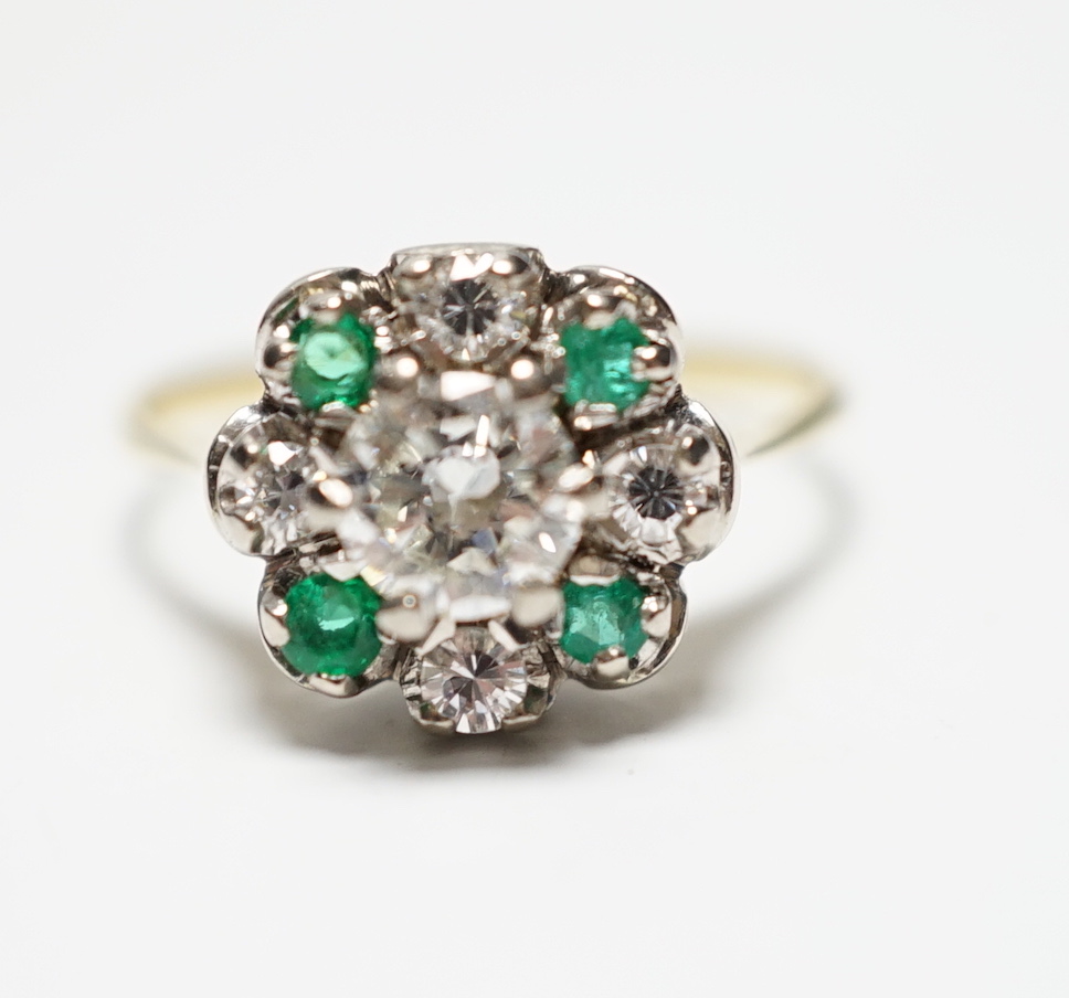 A yellow metal, diamond and emerald set flower head cluster ring, size P, gross weight 4 grams, the central diamond measuring approximately 5.5mm in diameter.